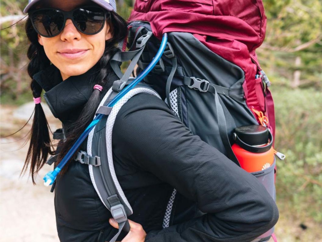 A woman with sunglasses and backpacking gear on